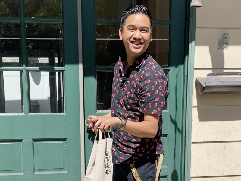 man smiling and happy, standing in front of a door with a door mat